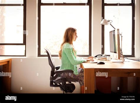 Side view of businesswoman using computer at office desk Stock Photo ...