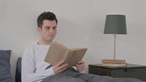 Hombre Leyendo Un Libro Sentado En La Cama Imagen De Archivo Imagen