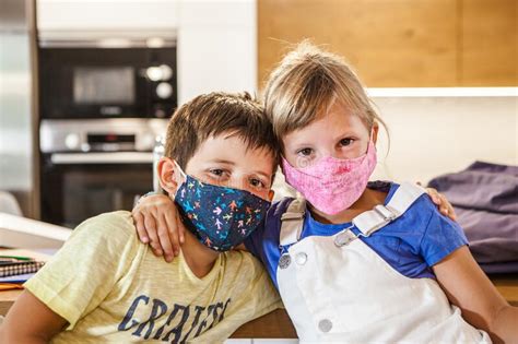 Niños Preescolares Con Máscaras Protectoras Y Mochilas Hablando Foto de