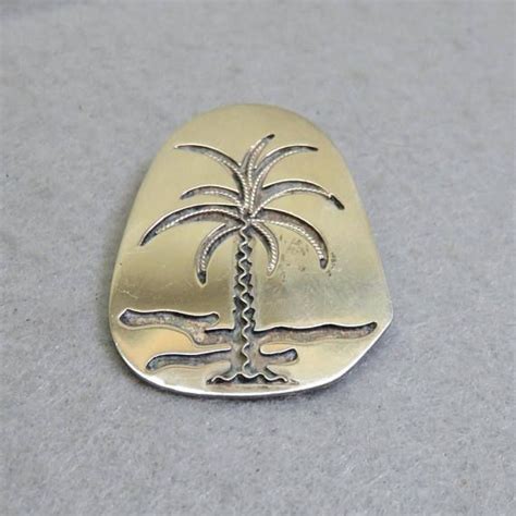 A Palm Tree Is On Top Of A Gold Plated Metal Brooch Or Pin