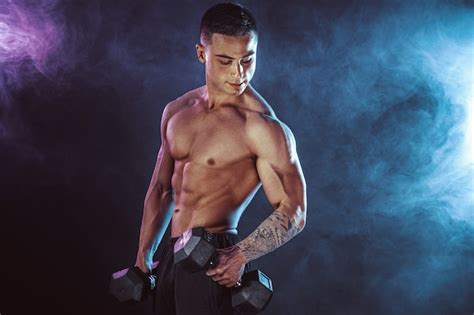 Premium Photo Athletic Man Training Muscles With Dumbbells In On Dark