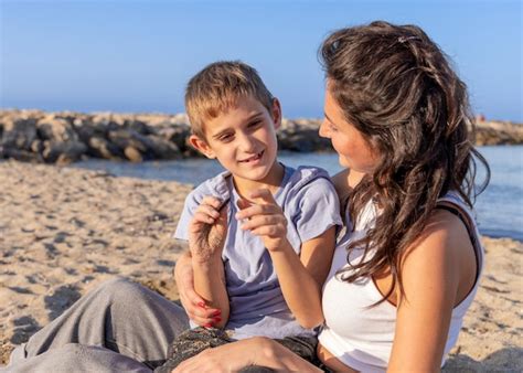 Feliz madre e hijo jugando en la playa en un día soleado en sundet