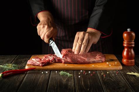 Premium Photo The Chef Cuts Raw Fresh Beef Meat On A Cutting Board