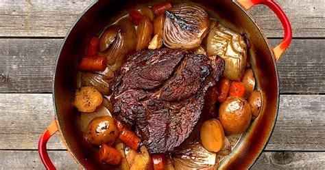 A Pot Filled With Meat And Vegetables On Top Of A Wooden Table