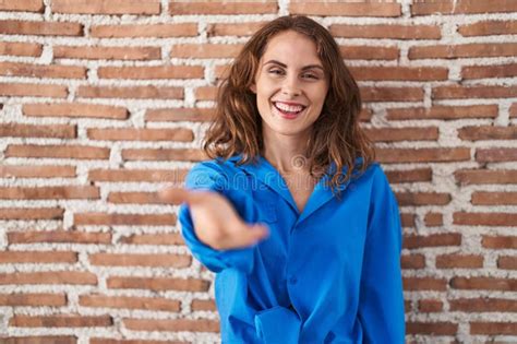 Beautiful Brunette Woman Standing Over Bricks Wall Smiling Friendly Offering Handshake As