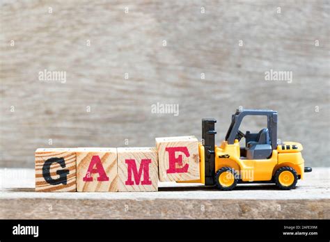 Toy Forklift Hold Letter Block E To Complete Word Game On Wood