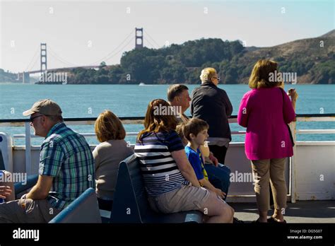 Sightseers approach Sausalito, California on a ferry boat with the Golden Gate Bridge seen in ...