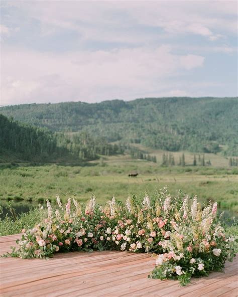 An Outdoor Ceremony Setup With Flowers And Greenery On The Ground In