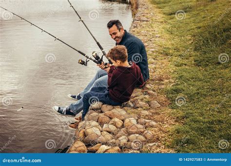 Father And Son Enjoying Fishing Sitting Near The Lake Stock Image