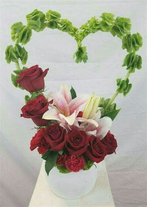 A Heart Shaped Arrangement With Roses Lilies And Carnations In A White