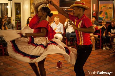 two people in red shirts and white skirts dancing with other people sitting on the sidelines