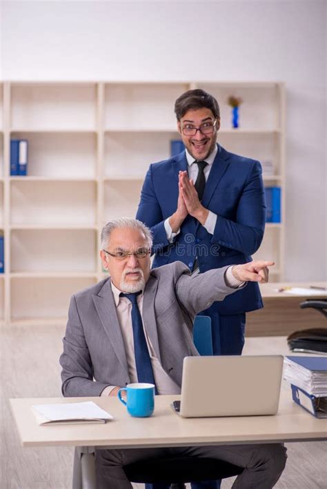 Jefe Masculino Viejo Y Empleado Joven En La Oficina Imagen De Archivo