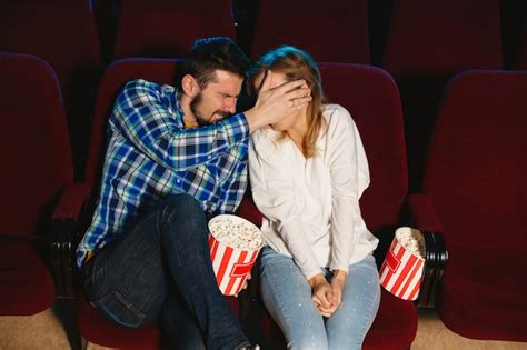 映画館、家または映画館で映画を見ている魅力的な若い白人カップル。 無料の写真