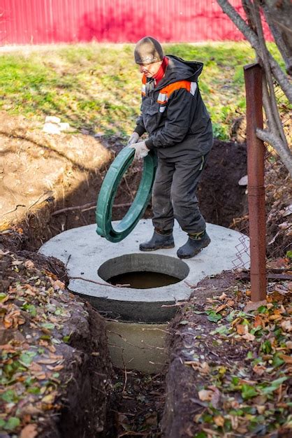 Premium Photo A Worker Installs A Sewer Manhole On A Septic Tank Made