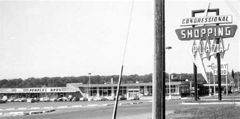 An Old Black And White Photo Of A Shopping Plaza With Cars Parked In