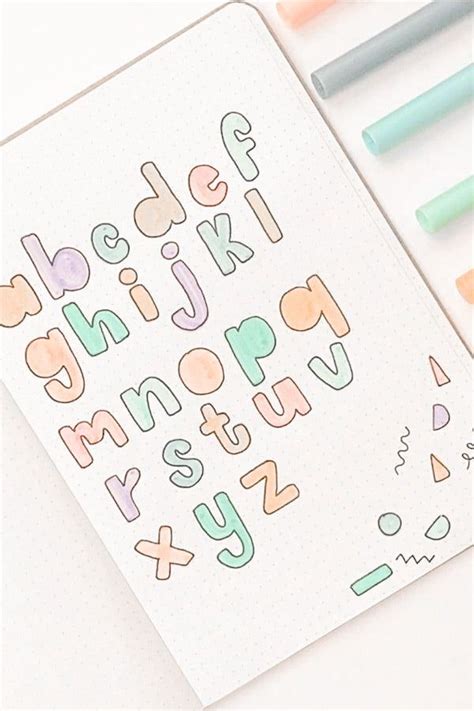 An Open Notebook With Colorful Lettering And Markers On It Next To Some