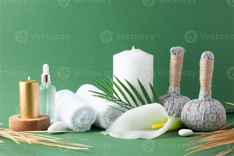 Spa treatment with herbal bag, candles and palm leaf on green background. Close up, copy space ...