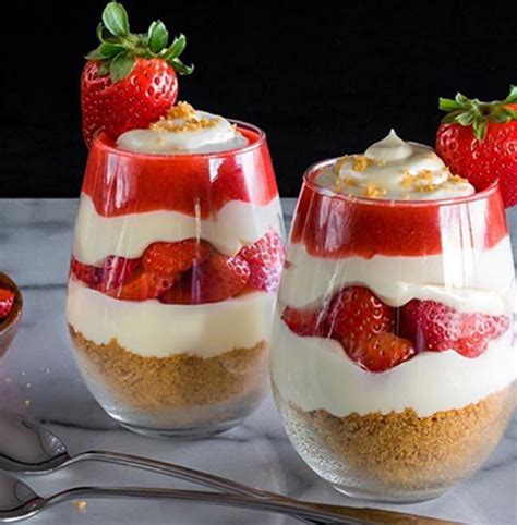 Two Desserts With Strawberries In Them On A Table