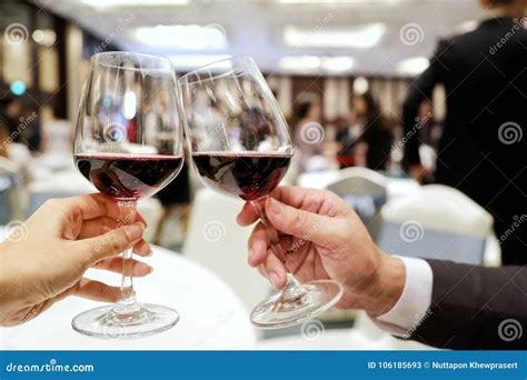 Two Persons Clinking Glasses Of Rich Red Wine In A Party Stock Image