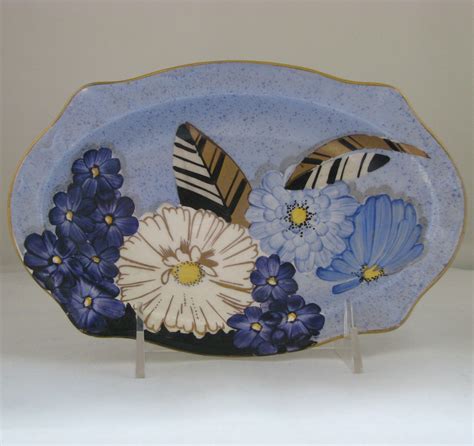 A Blue Plate With Flowers And Feathers On The Edge Is Sitting On A