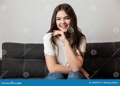 Portrait Of Young Beautiful Smiling Brunette Woman Sitting On The Sofa