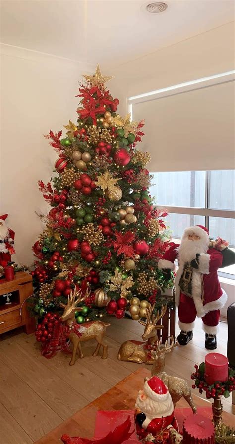 A Living Room With A Christmas Tree Decorated In Red Gold And Green