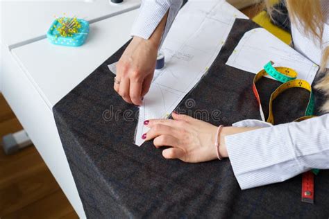 Dressmaker Marks Piece Of Fabric With Chalk According To Paper Pattern