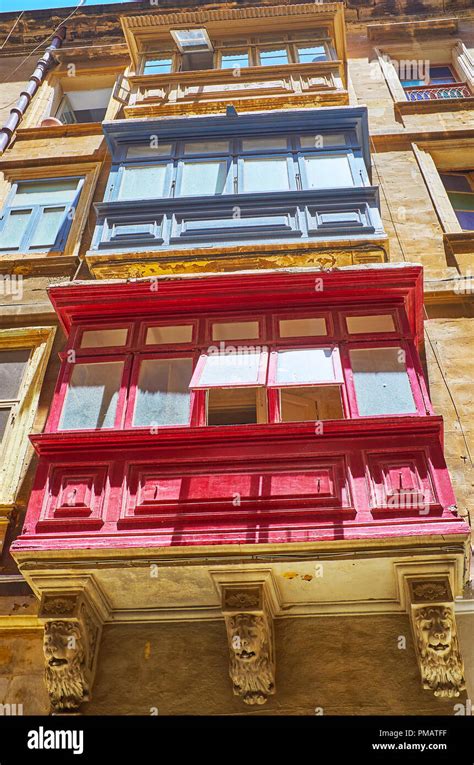 The Bright Colored Maltese Balconies Decorate The Facade Wall Of Old Stone Building In St