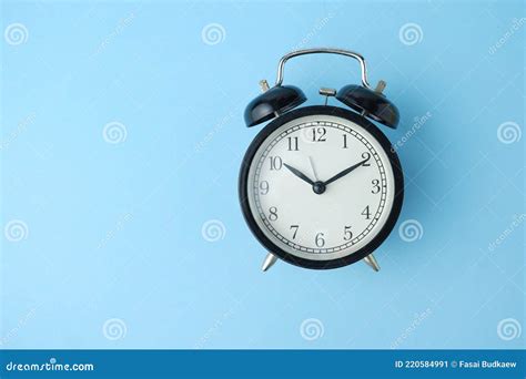 Reloj Despertador Negro Aislado Sobre Fondo Azul Imagen De Archivo