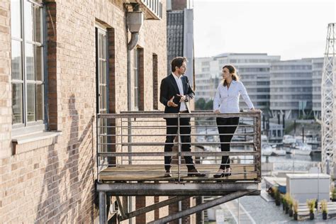 Business People Standing On Balcony Discussing Stock Photo