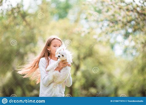 Petite Fille Souriante Jouant Et Serrant Chiot Dans Le Parc Photo Stock