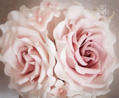 Two Large Pink Roses In A Glass Vase On A White Tablecloth With The