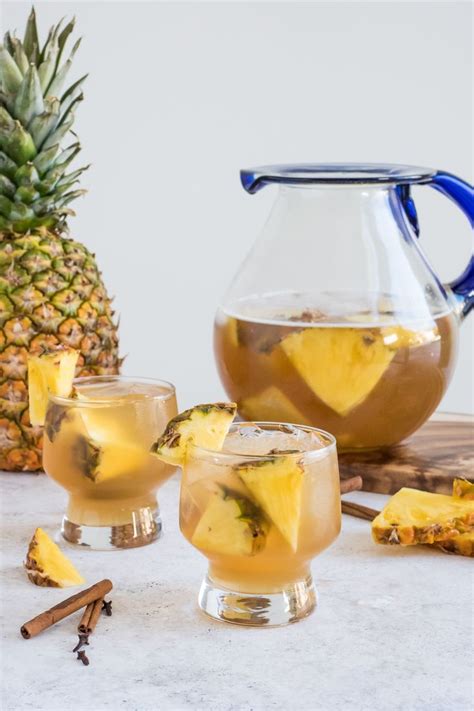 Two Glasses Filled With Pineapple Tea Next To A Pitcher