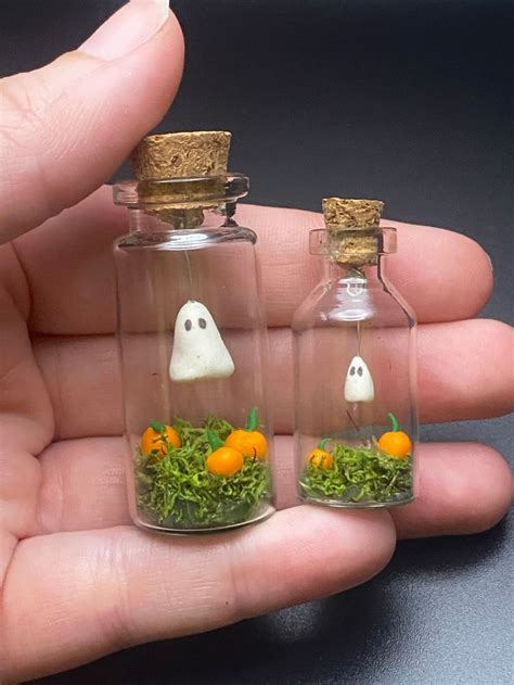 Two Miniature Bottles With Fake Grass Inside And Ghost Heads In The Top