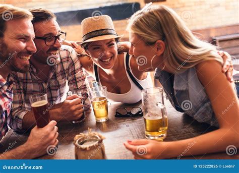 Pares Novos Que Bebem A Cerveja E Que Riem Junto Na Barra Foto De Stock