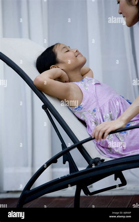 Side Profile Of A Daughter Lying On A Lounge Chair With Her Mother