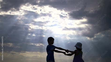 Silhouette Couple Children Having Fun Holding Hands Against The Sky At