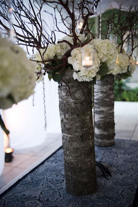 Two Tall Vases Filled With White Flowers And Branches