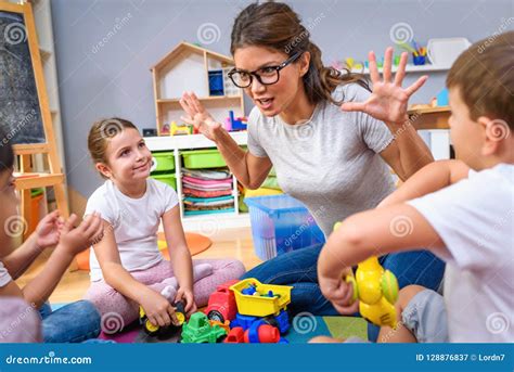 Preschool Teacher Talking To Group of Children Sitting on a Floor at ...