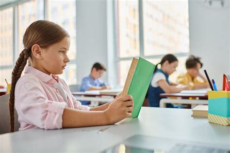 Uma Jovem Garota Se Senta Em Uma Foto De Stock Imagem De Concentrado