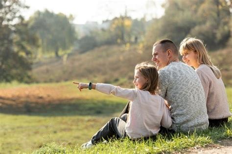 Three People Sitting On The Ground Pointing At Something In The