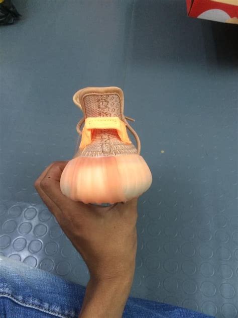 Someone Is Holding Up A Shoe That Has Been Made Out Of An Orange Piece