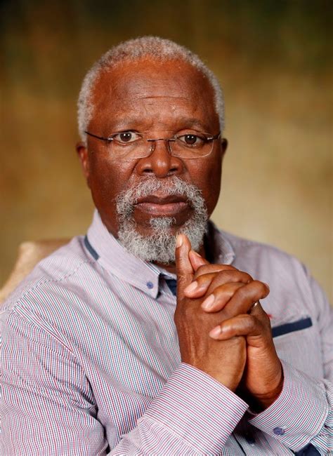 An Older Man With Glasses And A White Beard Is Sitting In A Chair