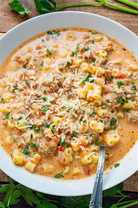 A White Bowl Filled With Pasta And Meat Soup On Top Of A Wooden Table