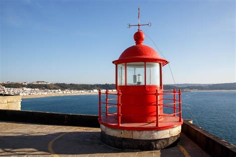 Sala da lâmpada do farol vermelho no fundo do céu azul e do mar Foto