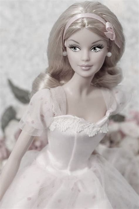 A Barbie Doll Wearing A White Dress With Pink Flowers On The Wall In