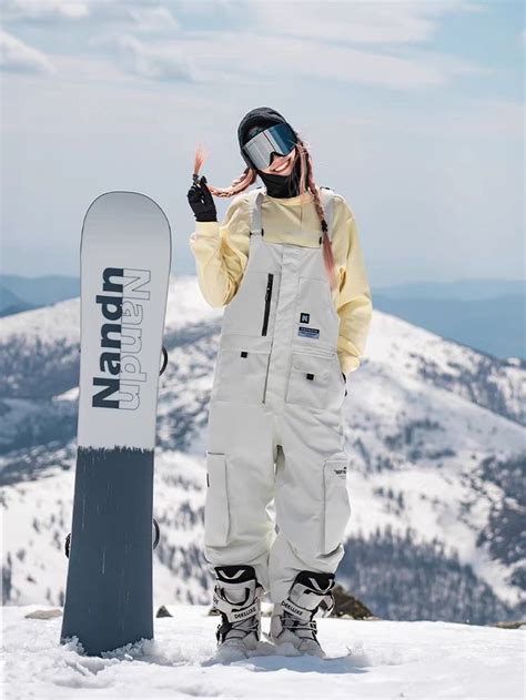 A Snowboarder Standing On Top Of A Mountain With His Board In Front Of Him