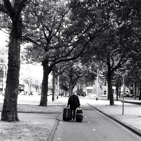 Black And White Photograph Of A Person Pulling Luggage Down The Street