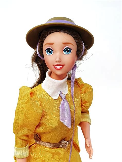 A Doll With Blue Eyes Wearing A Yellow Dress And Purple Hat Holding A