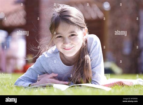 Girl lying on grass reading Stock Photo - Alamy